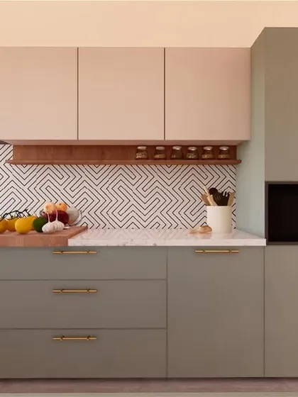 A modern kitchen design using a two-tone color scheme of sage green and beige. The geometric patterned backsplash adds a playful touch, while the open spice rack is a practical and stylish detail.