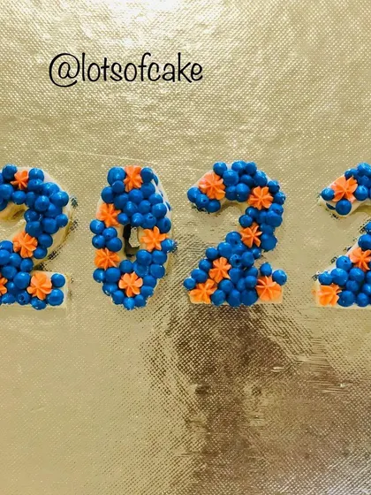 Celebrating the New Year with a trendy cream tart cake. This eggless cake is shaped into numbers and meticulously decorated with Russian buttercream frosting, showing a fun and stylish way to mark any occasion.