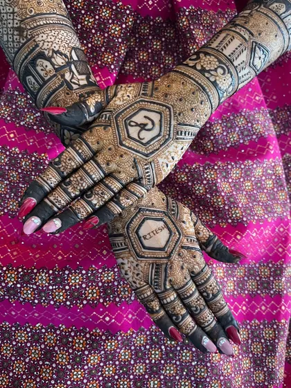 A crossed-hands pose, highlighting the intricate patterns of the back-hand mehendi.