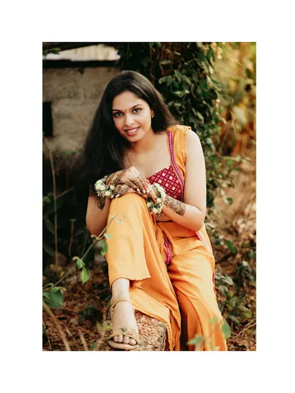 A relaxed and beautiful portrait of the bride sitting in a natural setting during her Haldi ceremony.