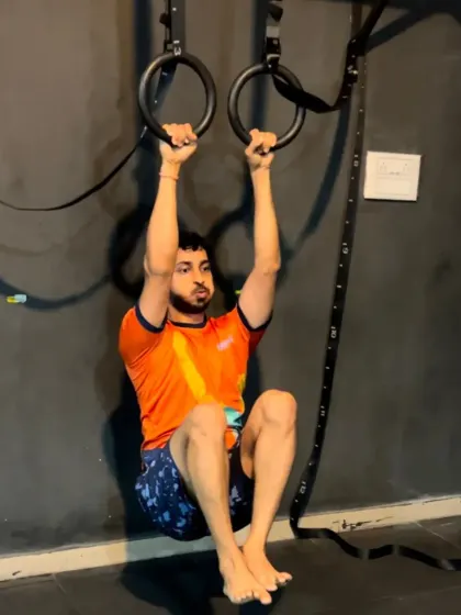 A member working on L-sits on the gymnastics rings. This is an advanced move that requires immense core and upper body strength, built over time.