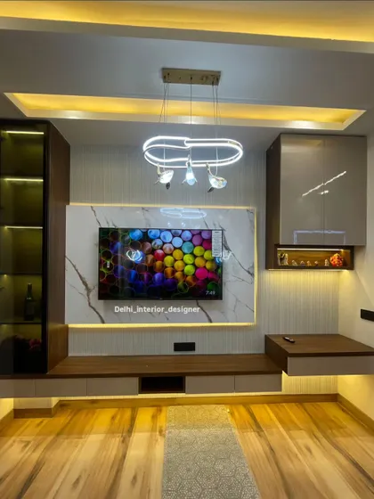 This bedroom features a complete entertainment and storage wall. The TV unit is designed with a mix of wood, marble finish, and illuminated display sections.