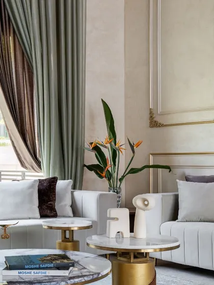 We carefully selected every piece of decor to complement the room's grand aesthetic. Here, the soft textures of the sofa and curtains contrast with the metallic accents of the side tables.