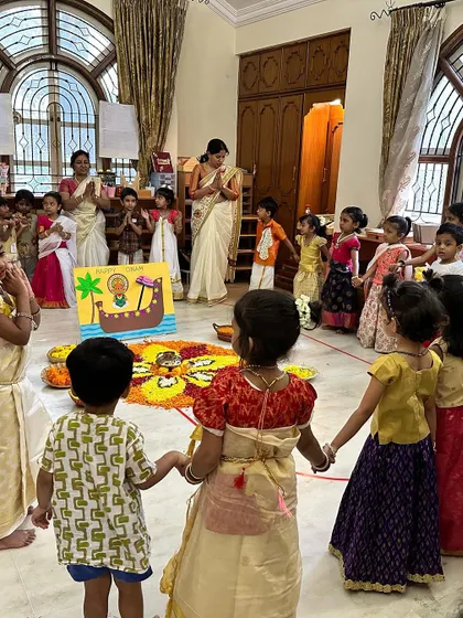 Children join hands to sing and dance around the pookalam, learning about the community aspect of festivals.