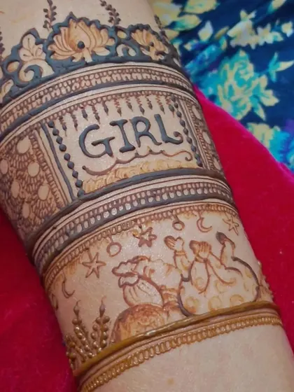 A close-up of the arm detail from the baby shower design. It shows the word 'GIRL' with a cute drawing of a stork carrying a baby, surrounded by stars and the moon.