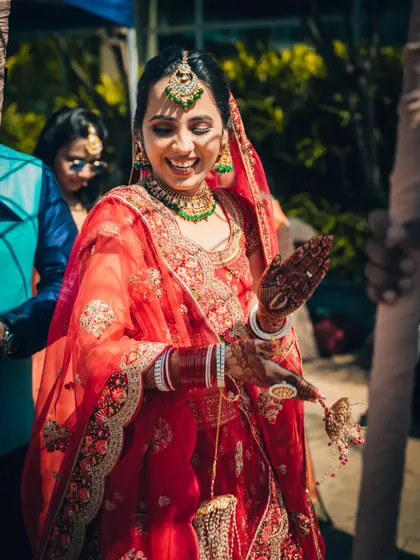A candid shot of a bride's joyful reaction during her wedding ceremony, her hands adorned with henna.