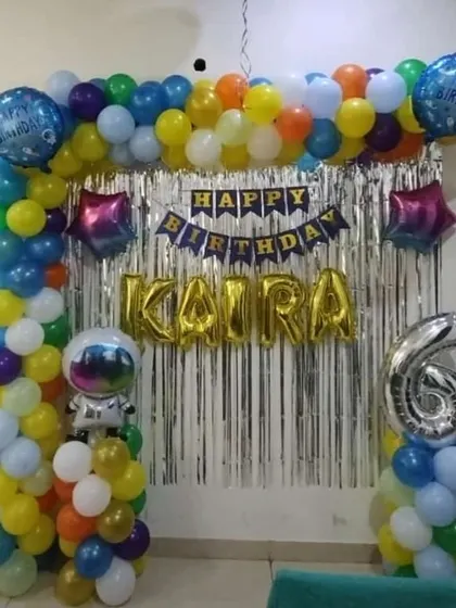 A space-themed birthday party for a 6-year-old. The decoration includes a colorful balloon arch with an astronaut foil balloon and a silver foil curtain.