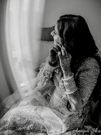 A beautiful black and white portrait of the bride getting ready. The motion blur from the curtain adds a dreamy, artistic touch to the image.