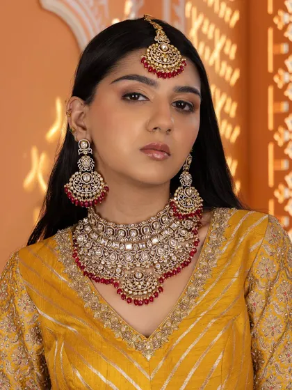 This full view highlights the grandeur of our red Kundan bridal set, complete with a statement choker, matching chandbali earrings, and an ornate maang tikka.