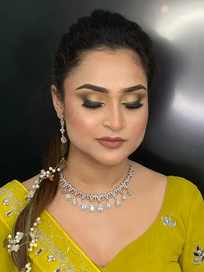 A still image of a glamorous engagement makeup look with the model's eyes closed, highlighting the expertly blended gold and black eyeshadow.