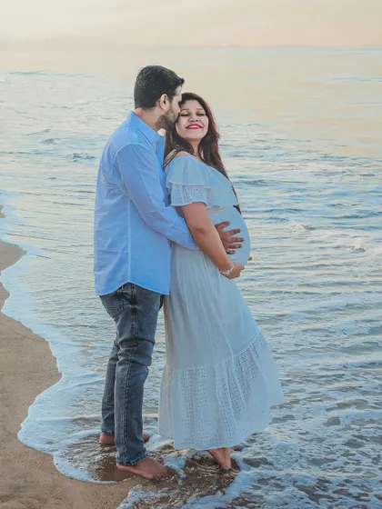 An outdoor maternity photoshoot at the beach, capturing a quiet moment between the expecting couple. The soft evening light and gentle waves create a serene and romantic backdrop for your pregnancy portraits.