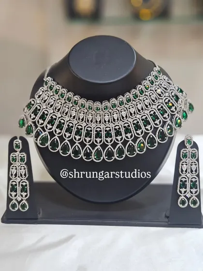 For the modern bride who loves to sparkle, this American Diamond necklace set is a showstopper. The silver-plated design is studded with high-quality AD stones and vibrant green gems, perfect for your sangeet, reception, or cocktail party. It gives you the look of real diamonds without the hefty price tag.