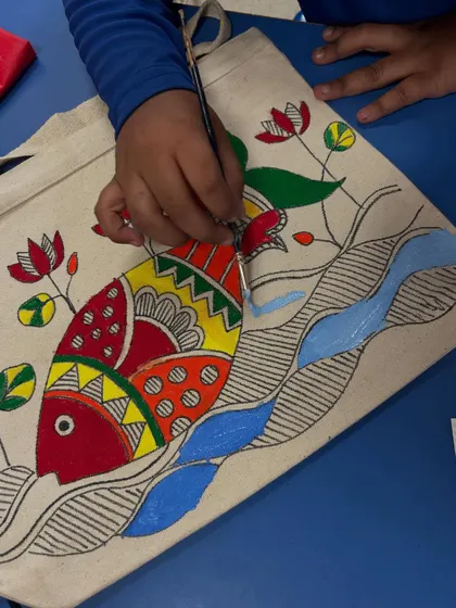 A close-up of a student carefully painting a Madhubani fish. It's a process that requires focus and patience, and the results are so rewarding.