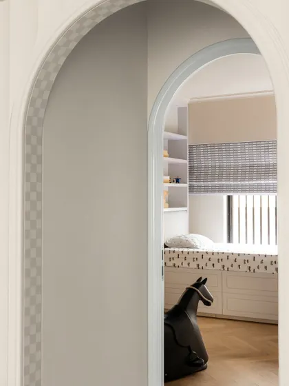 A peek into a child's room through an arched doorway, where a rocking horse waits for playtime.