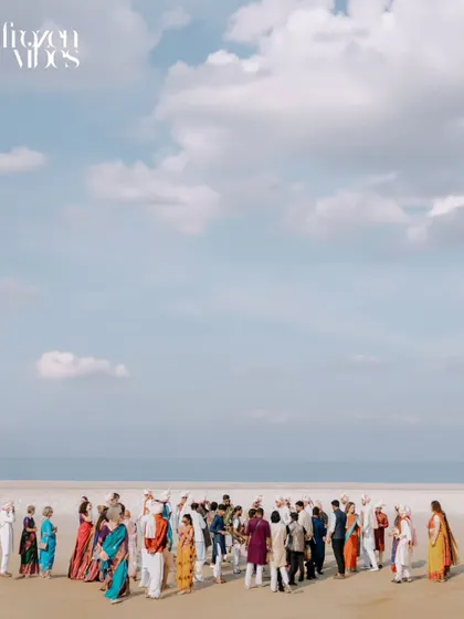 A wide, minimalist shot of the wedding party on a vast, empty beach. This artistic photo uses negative space to create a powerful and memorable image.