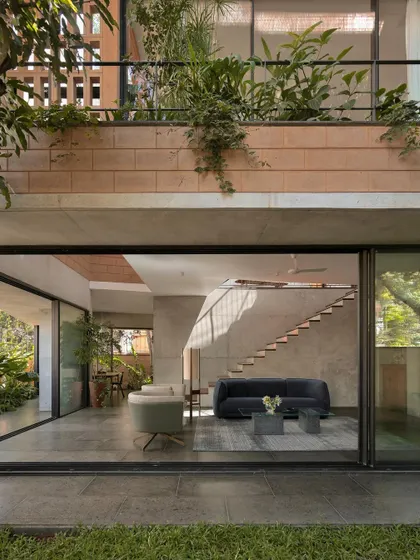 (Duplicate of 46) The living area of the Debris Block House seamlessly merges with the garden through expansive sliding glass doors, embodying our philosophy of tropical modern living.