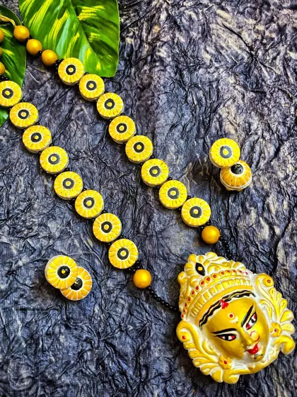 A majestic Durga face pendant on a long necklace made of yellow terracotta beads. This is a statement piece, perfect for festive occasions and a great centerpiece for a boutique's collection.