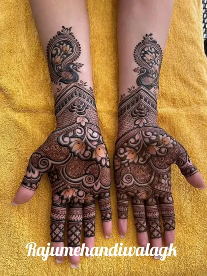 A beautiful example of a peacock-themed bridal design. The symmetrical peacocks on the wrists are the main focus, with their feathers flowing down into a mix of floral and paisley patterns on the hands.