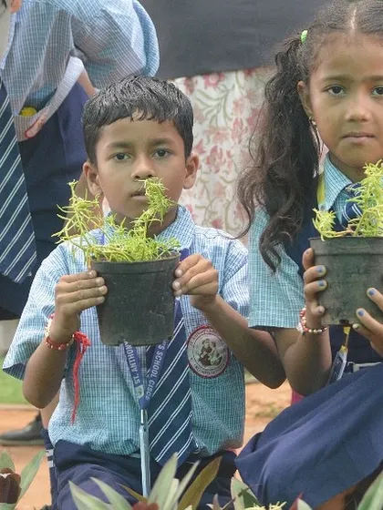 Two young students proudly holding the plants they've just potted. Giving them something to take home and nurture is a key part of the learning process.