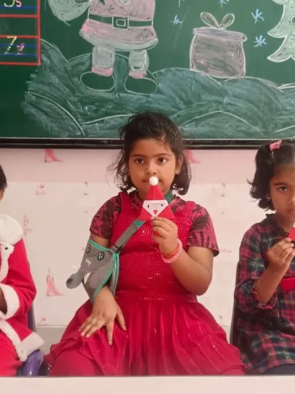 Three students show off their adorable handmade Santa crafts, complete with a fluffy cotton ball for the nose.