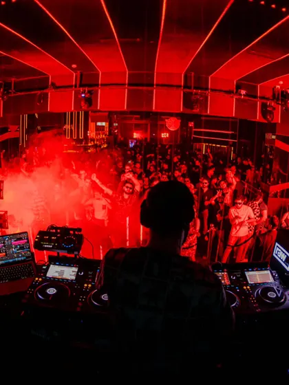 The view from behind the decks, looking out at a sea of people under the red lights. This is the raw club night energy I live for.