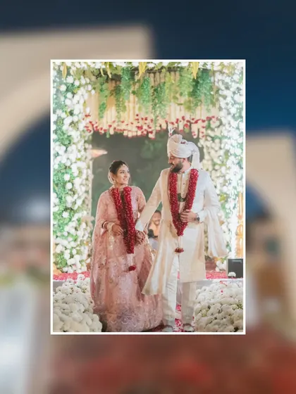 The couple walks hand-in-hand down a path of flowers, smiling at each other. This is a classic candid moment that captures the joy and partnership of the wedding day.