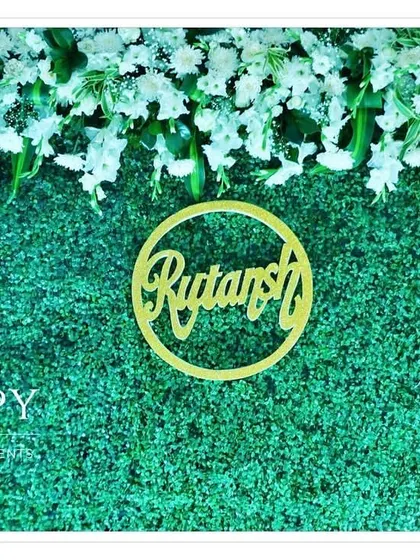 A close-up of the "Rutansh" name cutout against the lush green backdrop. We ensure every detail is perfect for your special day.