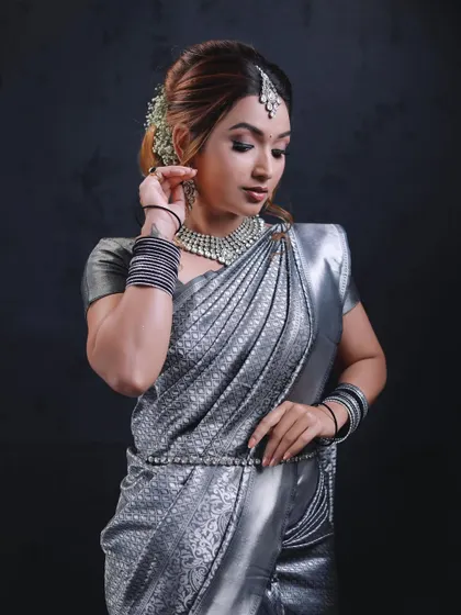This modern and chic look was created with a silver tissue silk saree for a demonstration. The drape is kept clean and sharp to highlight the saree's metallic sheen, perfect for a reception or cocktail event.
