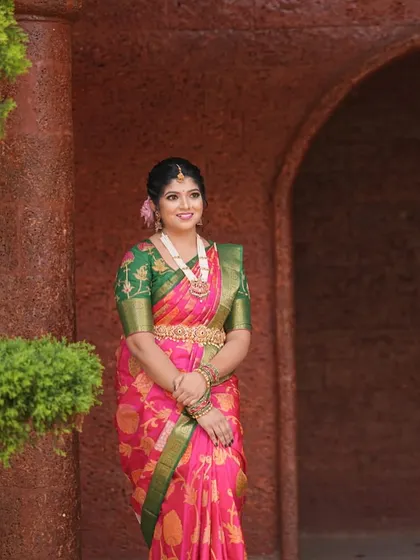 Our client Devika is draped in the opulence of this exquisite deep pink silk saree with a contrasting green border.