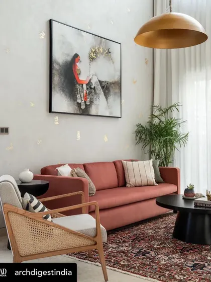 A living room from the same AD feature, with our caned accent chair and a deep terracotta sofa, adding warmth and texture to the neutral space.
