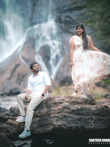 A creative pose with the groom looking up at his partner, set against the stunning waterfall backdrop.