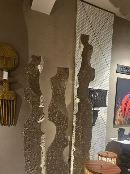 A collection of tribal and abstract art pieces on display. From a carved comb to elongated stone figures, these artifacts add a unique, global feel to any design.