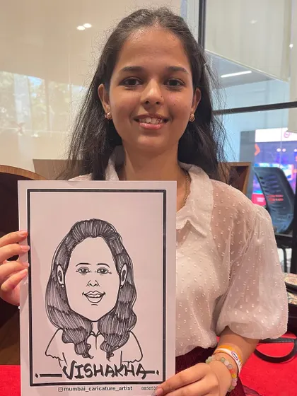 A student visiting the ITM booth at an event, happy with her new caricature.