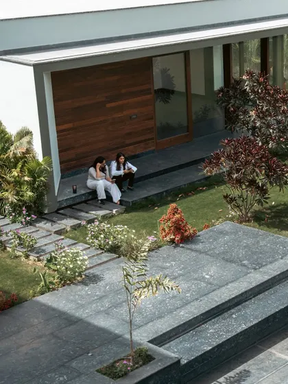 The pool house at Rosewood Farmhouse is nestled within the landscape, creating a perfect spot for outdoor entertaining. Here, two of our designers are seen enjoying the seamless transition from the built structure to the manicured lawn and layered garden beds.