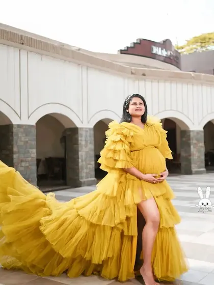This mustard yellow ruffled gown looks stunning against an architectural backdrop. The voluminous train and sleeves make it a true statement piece for any maternity photoshoot.