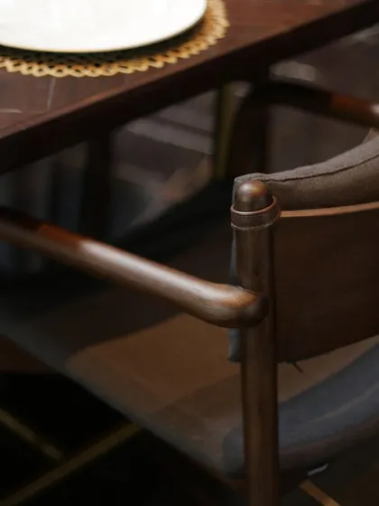 A close-up of a dining chair from our Axel collection, showcasing the fine craftsmanship of the solid wood frame and the texture of the fabric. Every detail is considered to bring warmth and elegance to your dining moments.