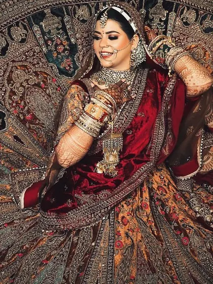 Another grand portrait of the bride seated on her intricately embroidered lehenga. This pose is perfect for showcasing the stunning craftsmanship of her wedding dress.