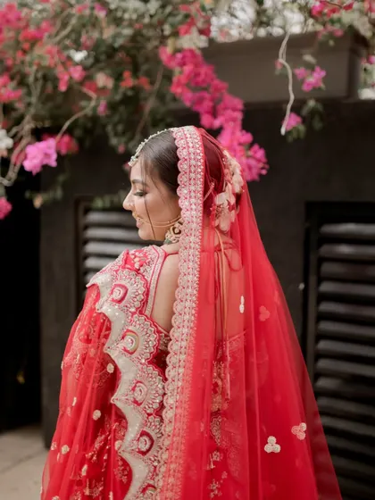 A close-up from behind, focusing on the bride's elegant hairstyle and the details of her red veil.