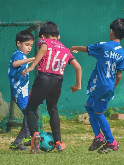 A tight tussle for the ball between three young players.