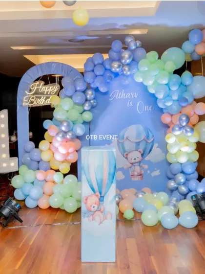 A full view of Atharv's hot air balloon themed first birthday. The pastel blue balloon arch, custom backdrop, and light-up number '1' create a dreamy and picture-perfect setting.