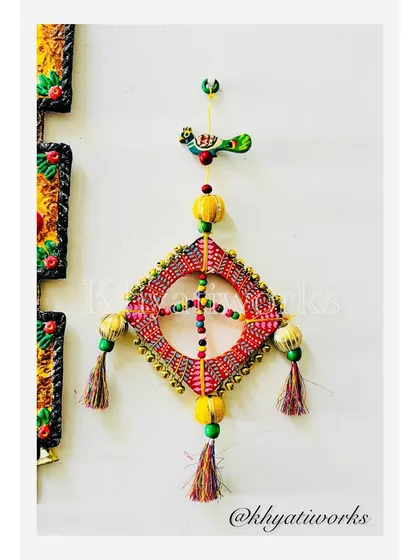 Celebrate the kite season with this handcrafted wall art. It's made on a wooden frame and adorned with ghungroos, beads, and playful tassels to capture the magic of the festival.