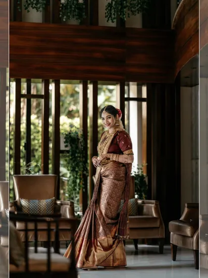 A beautiful bridal portrait in a modern, well-lit hotel lobby, her traditional saree contrasting with the contemporary background.