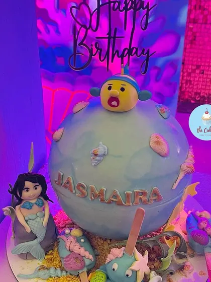 The mermaid piñata cake under party lights, showing its fun and unique design for a birthday celebration.