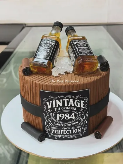 A vintage-themed Jack Daniel's barrel cake for a 1984 milestone birthday. The design includes miniature liquor bottles and edible cigars for a classic, masculine feel.