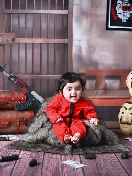 For the fans of 'Money Heist', we offer a unique and playful themed photoshoot. This creative setup, complete with iconic red jumpsuits and Dali masks, is a fun way to capture a different side of your little one's personality.