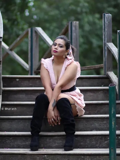 An edgy and fashionable portrait on a wooden bridge. The thigh-high boots and pose create a strong statement.