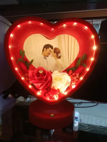 Another view of the red heart-shaped LED lamp, showing the vibrant red roses and the warm light that highlights the couple's photo.