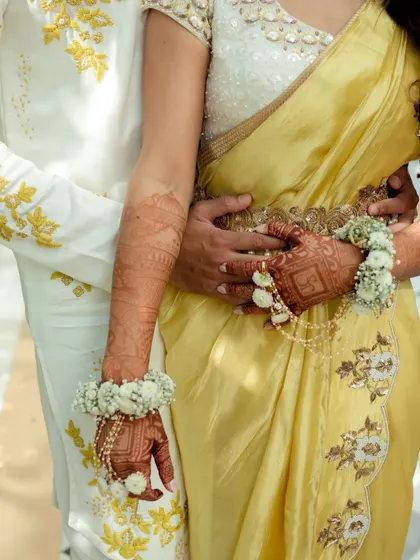 A close-up of the couple's hands, adorned with mehendi and floral jewelry. We focus on the beautiful details that make each ceremony unique.