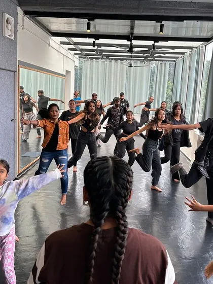 A view from behind, showing a class full of students learning and moving in sync.