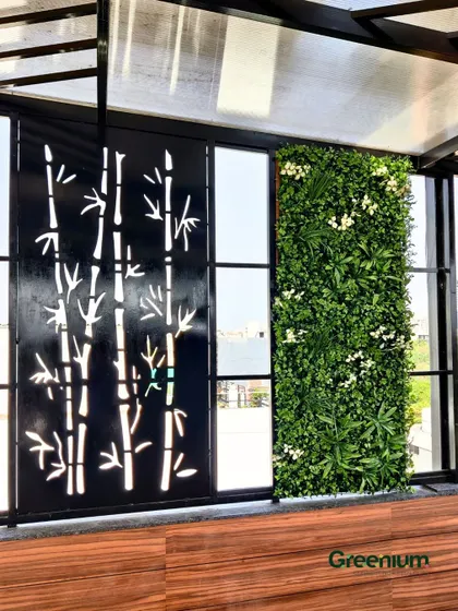 A wider view of the artificial green wall next to a decorative CNC-cut metal panel. This combination of nature-inspired patterns and greenery creates a unique and stylish feature.